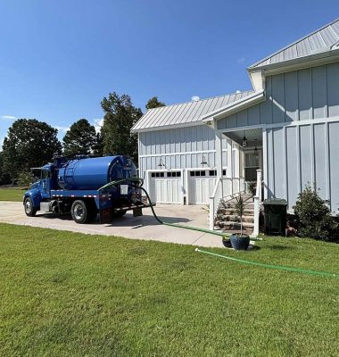 A blue truck parked in front of a house with a well-maintained lawn and a clear blue sky in the background.